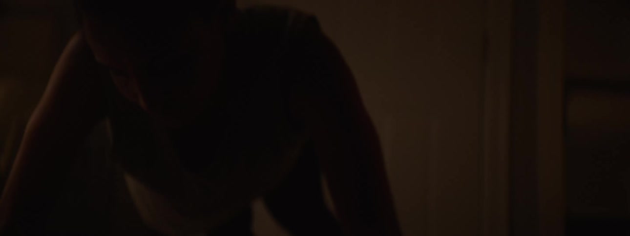 Young woman in a dark room doing intense pushups her body tense with effort and determination