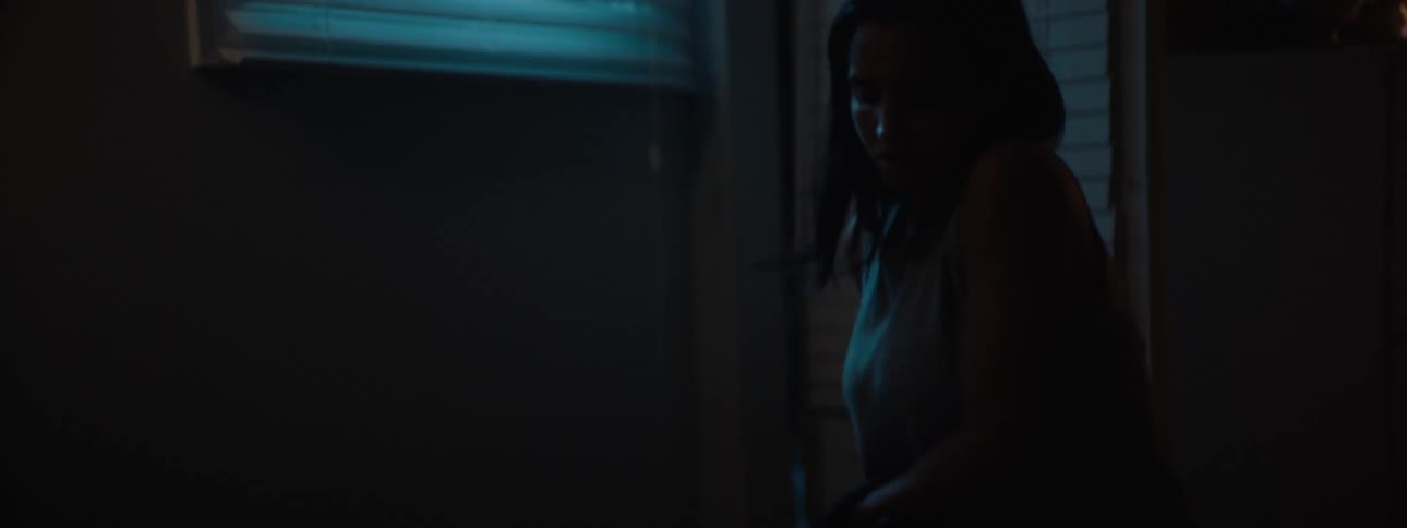 Young woman walking into her kitchen holding a stack of mail switching on the light and checking each piece one by one