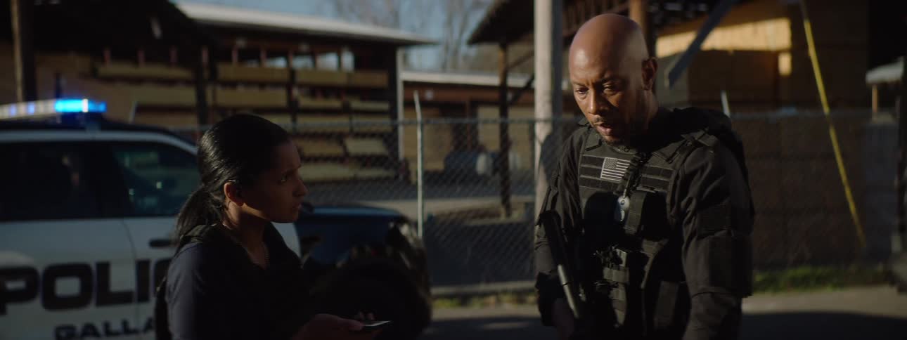 Two black police officers negotiating over a phone call while standing outdoors during daytime