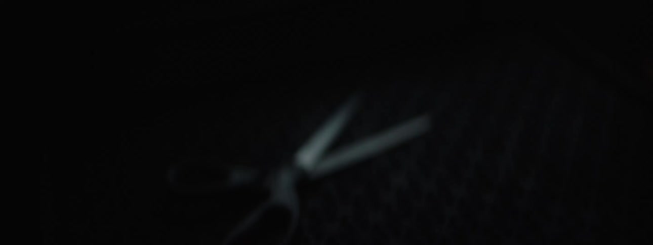 A pair of scissors is on a rubber mat in a darkened room