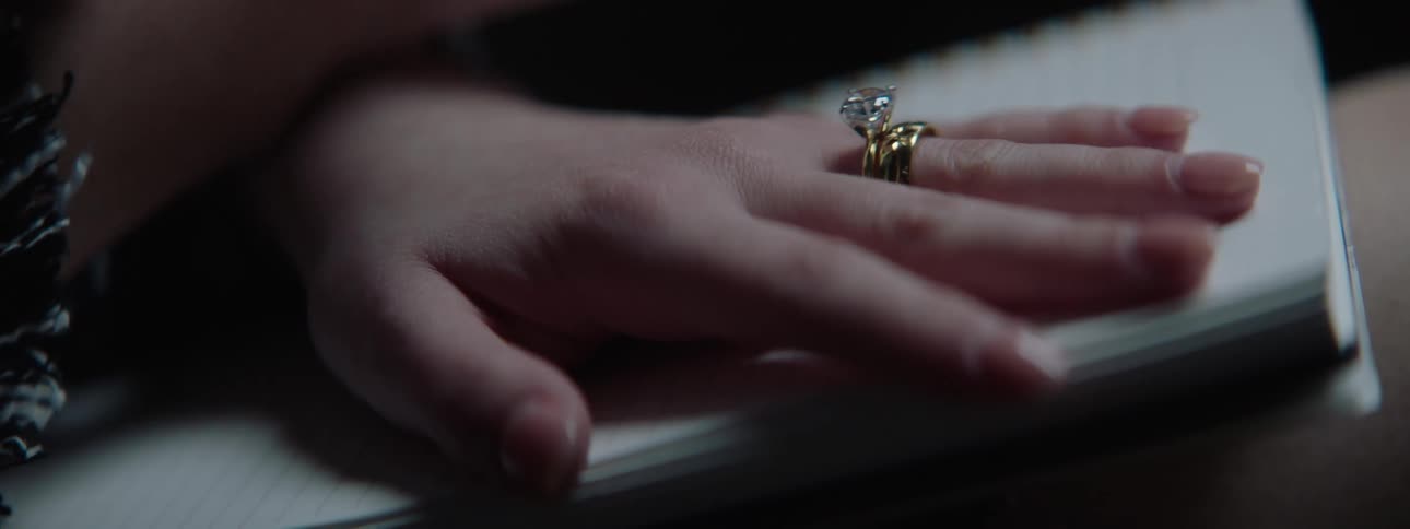A female nervously taps her finger and shakes a pen with her other hand