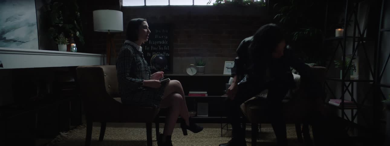 Two young women sitting in a living room at midday engaged in a discussion