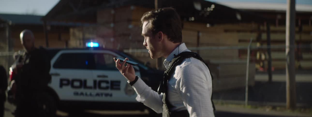 Close up of a police officer making a phone call while pacing around outdoors