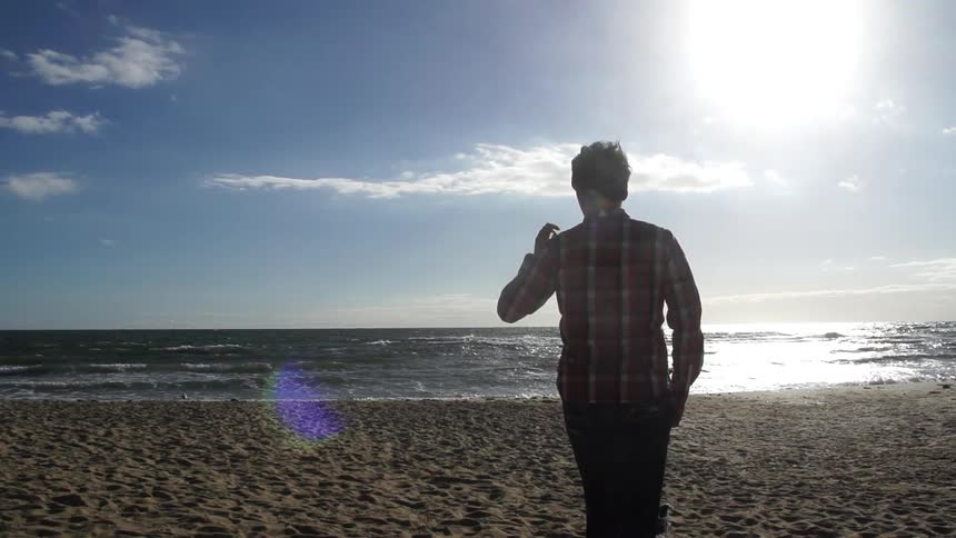 Man walks down the beach towards the water