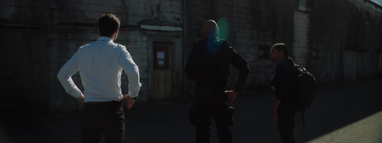 Three officers two men and one woman standing in the middle of the street at midday engaged in conversation