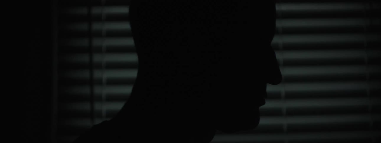 In a dark room the silhouette of a man is visible near a window