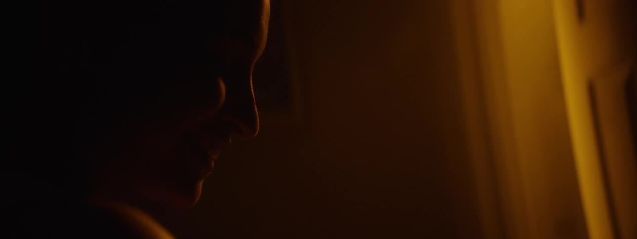 Woman smiling in a dark room lit by yellow light