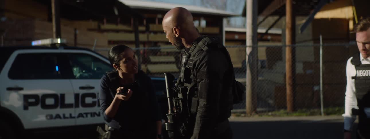 A group of police officers negotiating over a phone call while standing outdoors during daytime