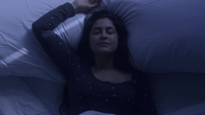A woman falls backwards into bed and lands atop two soft pillows
