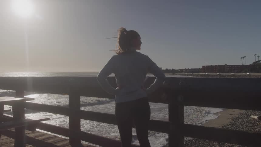 A young woman standing on a wooden pier outdoors during daytime