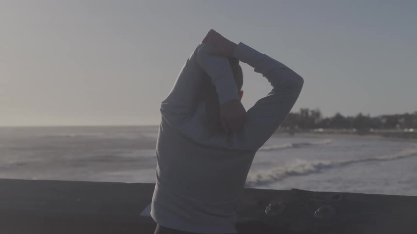 Woman at the seaside stretching her arms