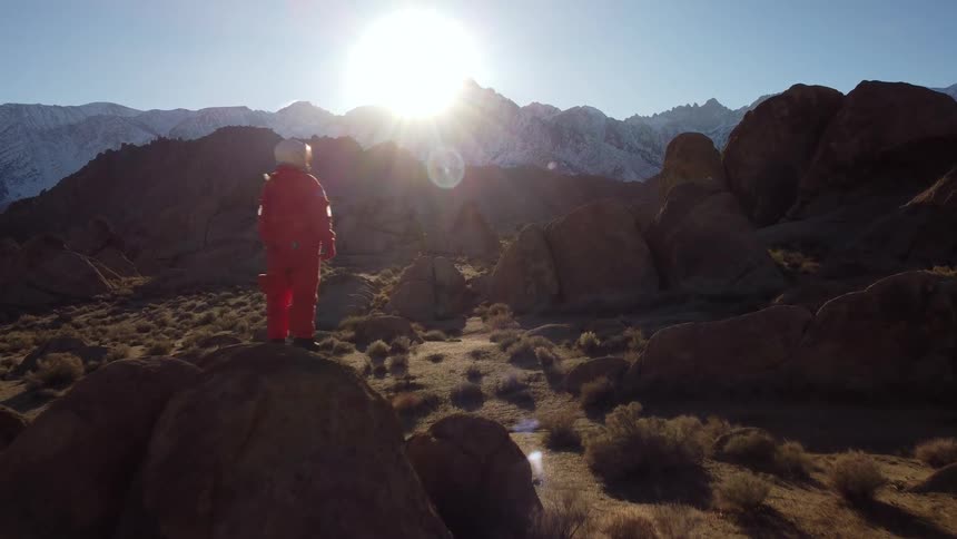 Astronaut on a rock in a natural setting by the mountains