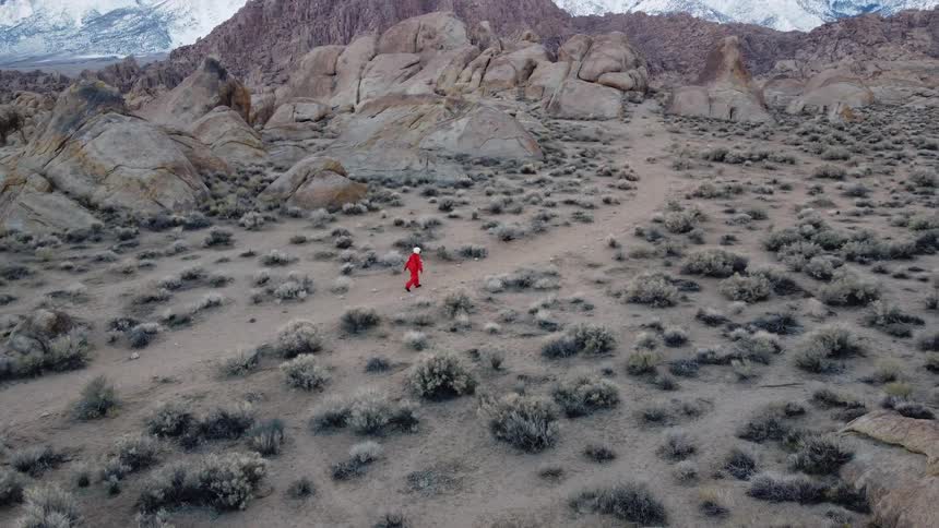 Person in orange clothing walking in a mountainous area