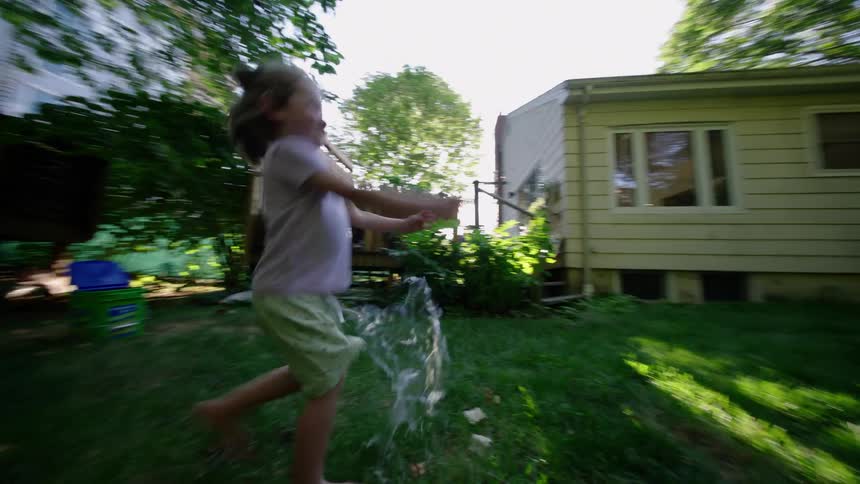 Child running in the backyard chasing a giant soap bubble