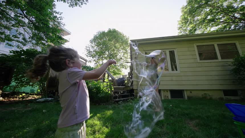 Mother and daughter in the backyard playing with soap bubbles