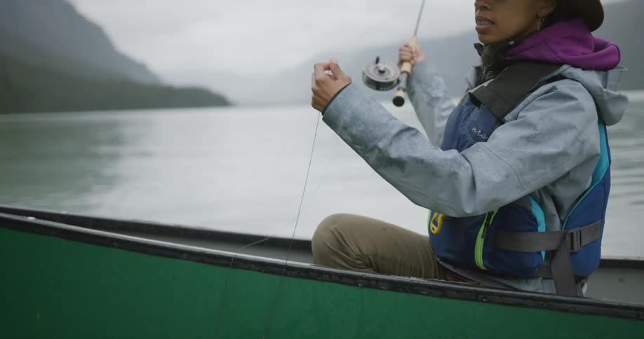 Person fishing in a green canoe using a fly fishing rod