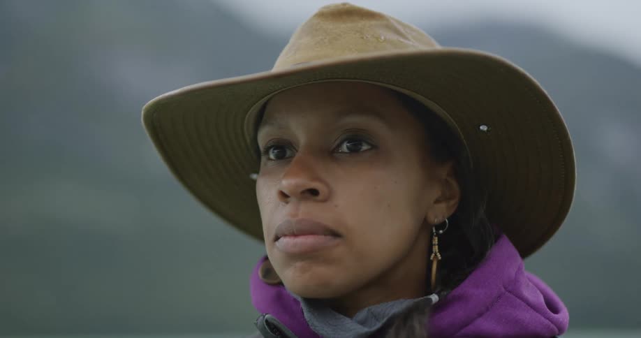 Woman wearing a brown hat and purple hoodie looking attentively ahead