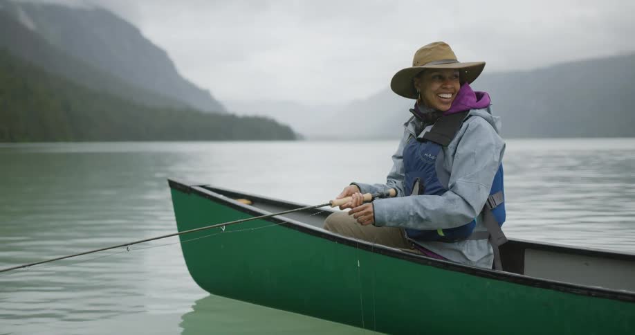 The woman smiles while fly fishing on the boat