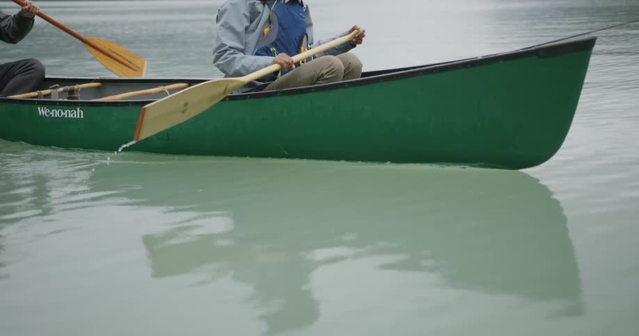 Man and woman on a boat at midday both using paddles together