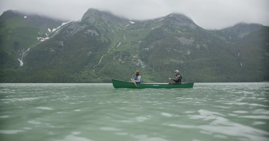 Man and woman on a boat at midday both using paddles together