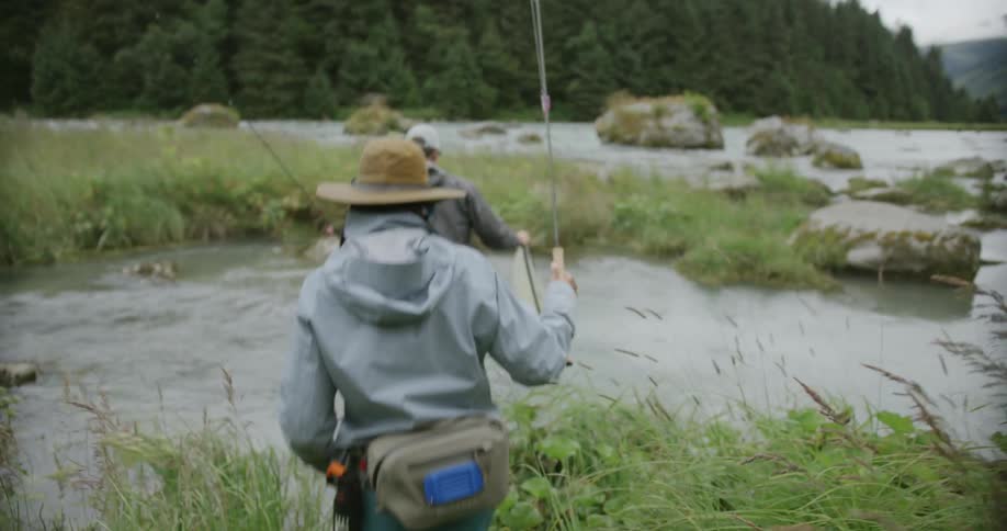 Fishermen cross the river carrying fishing rods