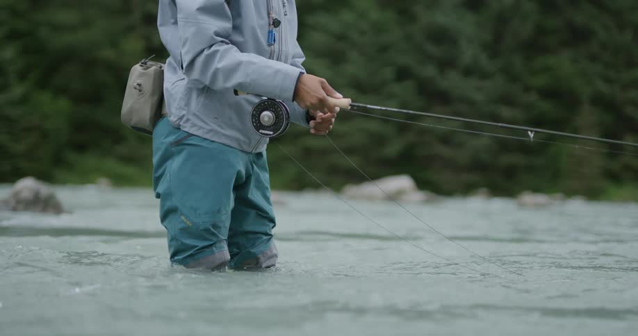 Man fishing standing with water up to his knees outdoors during day time