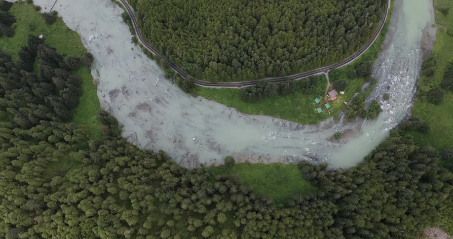 Aerial view of a winding river surrounded by dense forests with a road alongside