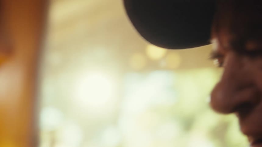 Elderly man wearing a baseball cap holding a smart phone in his hand indoors during day time