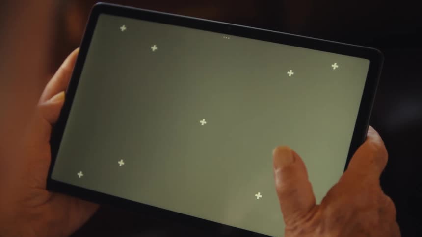 A persons hands hold a tablet and their finger moves on the screen