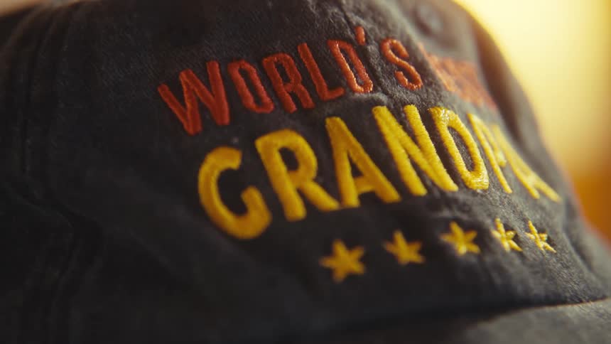 Blue cap with the saying worlds best grandpa on the head of a person indoors during day time