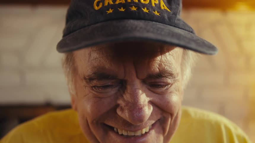 Smiling man wears a yellow shirt and a dark cap