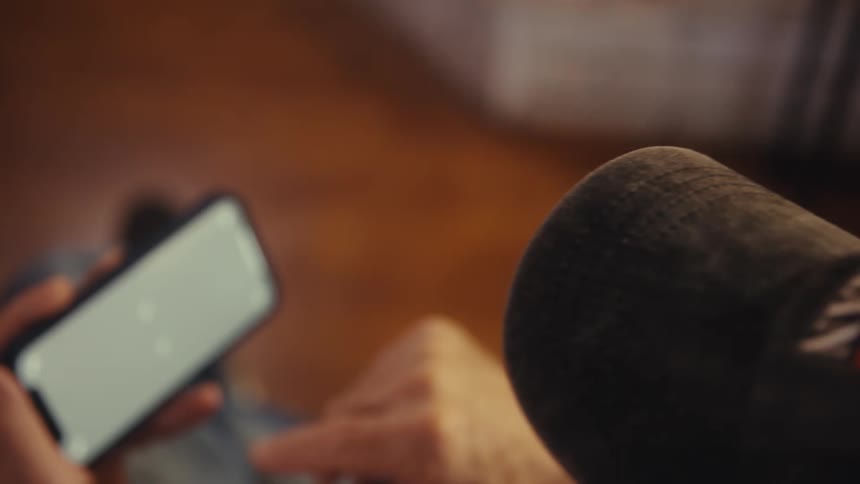 Person holds a cellphone while wearing a cap with an american flag detail