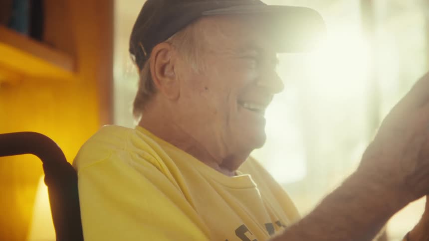 Man wearing a cap and yellow shirt smiles while looking forward