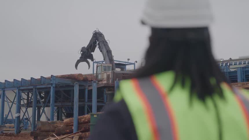 Construction worker stands on a work site looking towards an excavator