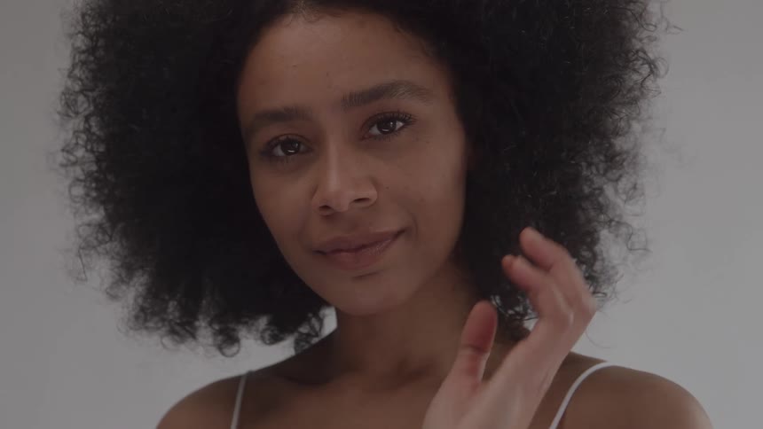 A close up portrait of a young woman with curly hair modeling in an indoor setting