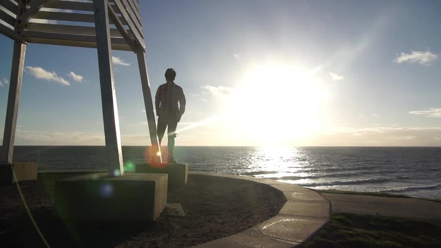 Man standing by the water at sunrise