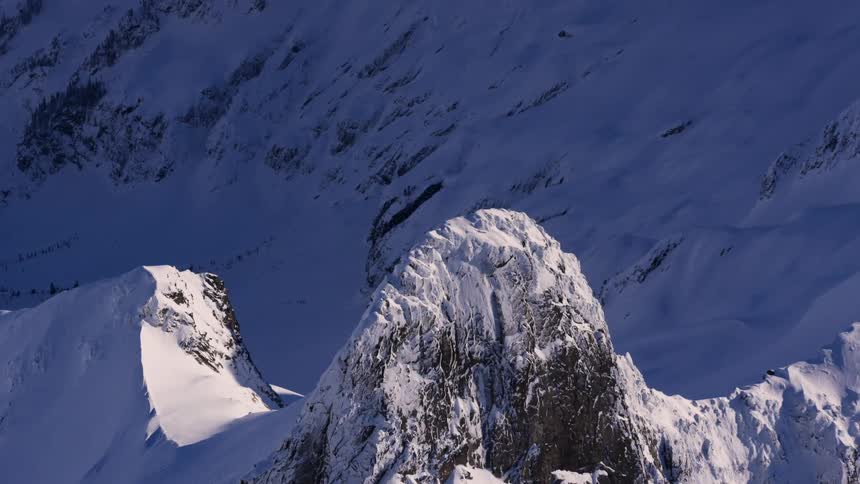 A mountain is covered in snow with a dark peak surrounded by other snowcovered mountains