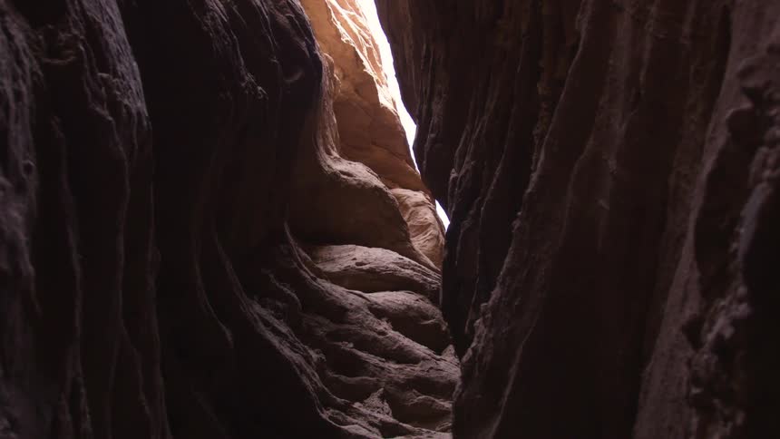 Sunlight shines into a narrow canyon between craggy cliffs
