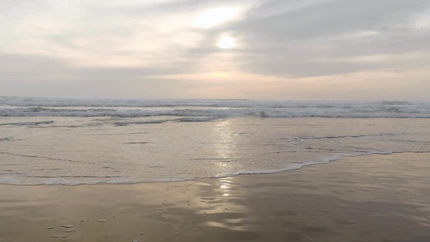 Slow motion of shallow ocean waves washing upon a sandy beach