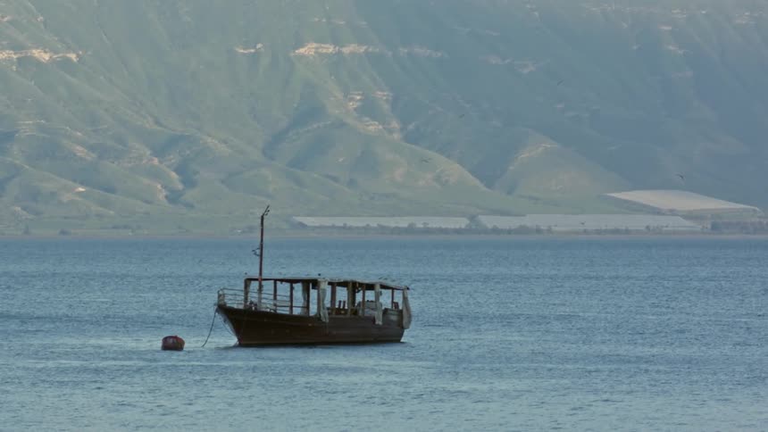 A boat is anchored offshore beside a mountain