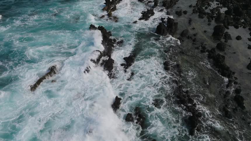 The ocean water crashes against the rocks on the shoreline