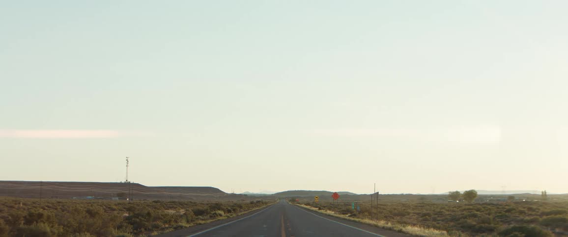 A straight road runs through a desert landscape under a clear sky