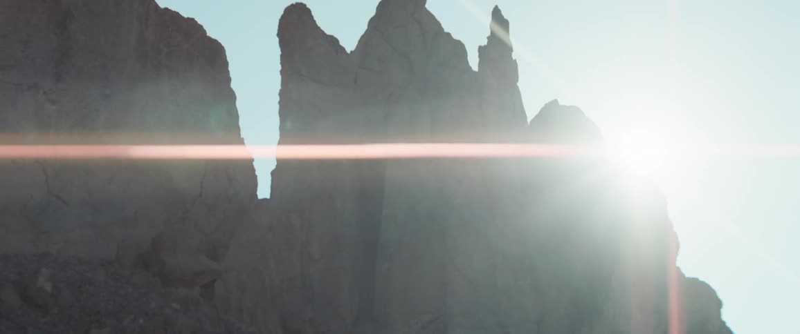 Tall rock formations are illuminated by the rising sun in the background