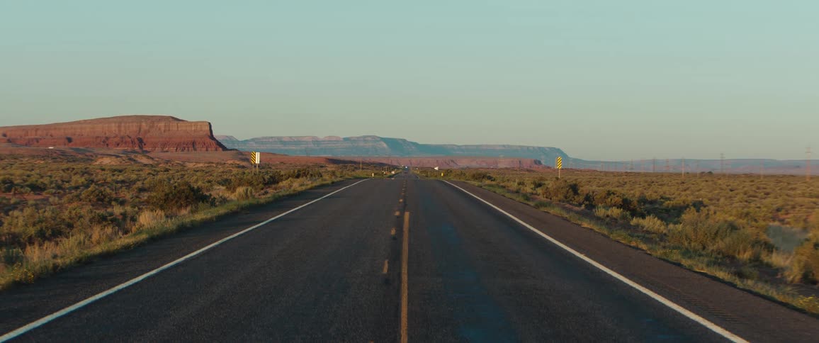 Empty freeway stretching through the countryside at midday with no cars in sight under the bright sun