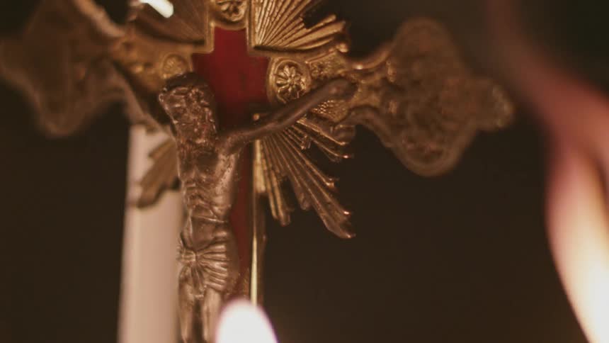 Candles burn near a crucifix