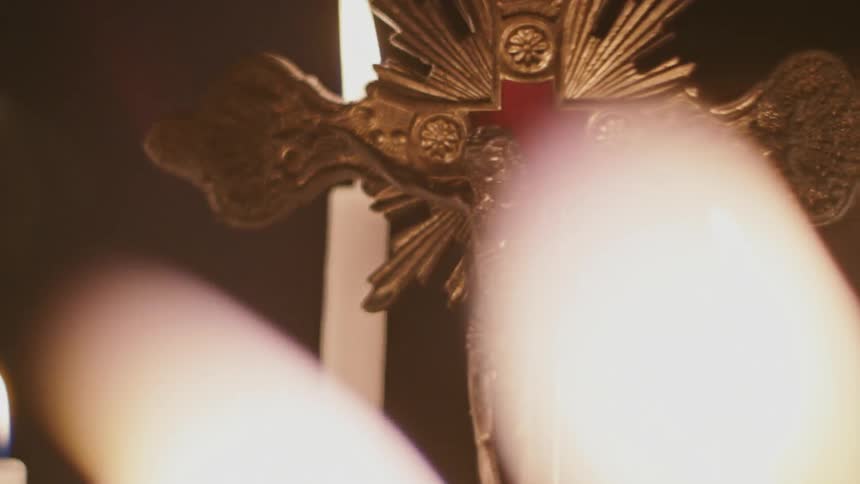 Candles burn near a crucifix