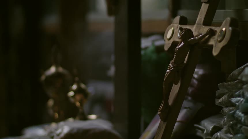 A crucifix is leaning against a wall while incense burns near it