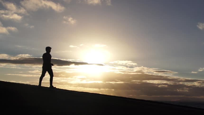Person walking as the sun sets behind
