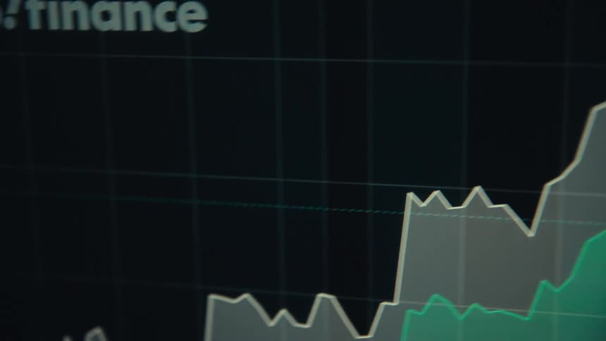 Numbers and a line chart are on the computer monitor