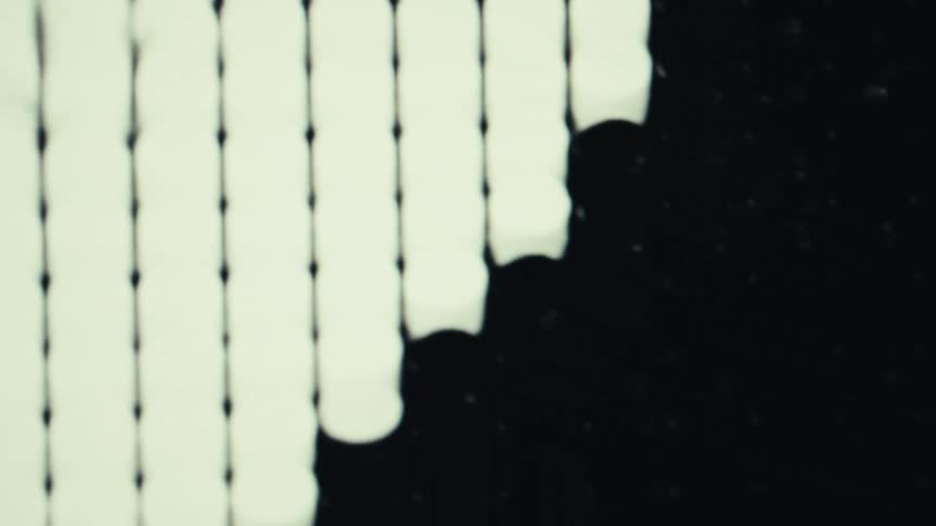A monochrome abstract video shows black and white blob shapes expanding dripping and merging on the screen